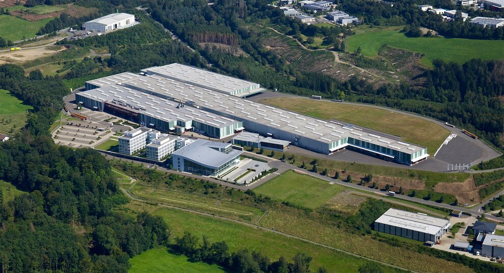 Vista aérea de las instalaciones de ABUS Kransysteme GmbH con naves de producción de grúas puente y componentes y la KranHaus de Herreshagen