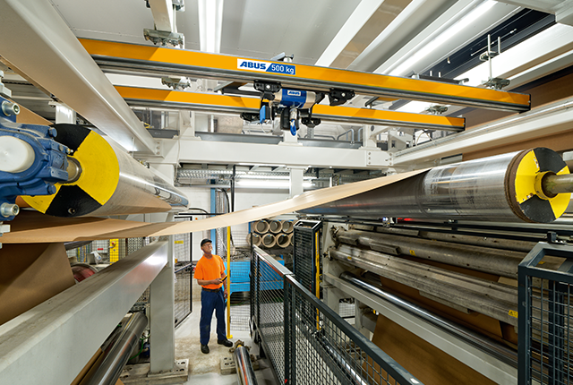 Un tren de dos raíles transporta material a lo largo de la línea de producción, mientras un empleado supervisa el proceso.