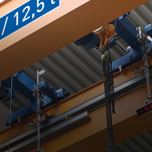 Carro birraíl ABUS, modelo D, instalado en una instalación de grúa con polipasto de cadena y una capacidad de carga de hasta 63 t.